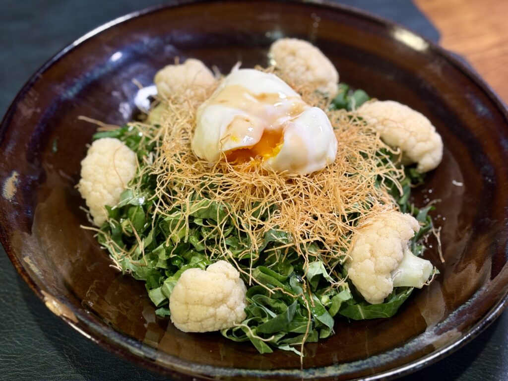 千切りケールに温泉卵をのせ、カダイフと粉チーズを散らしたサラダ