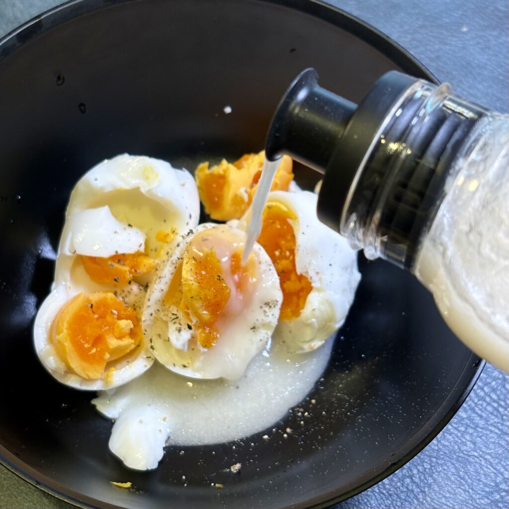 このドレッシングで“タルタルソース”が一瞬で完成 alt ゆで卵に白い醤油麹ドレッシングをかけている様子