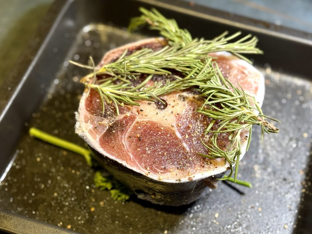 塩胡椒とガーリックパウダーで下味をしたマグロのテールにローズマリーをのせた様子