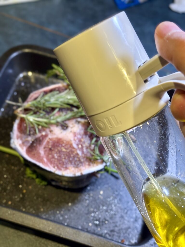 マグロのテールにオイルスプレーでオリーブオイルをかけている様子