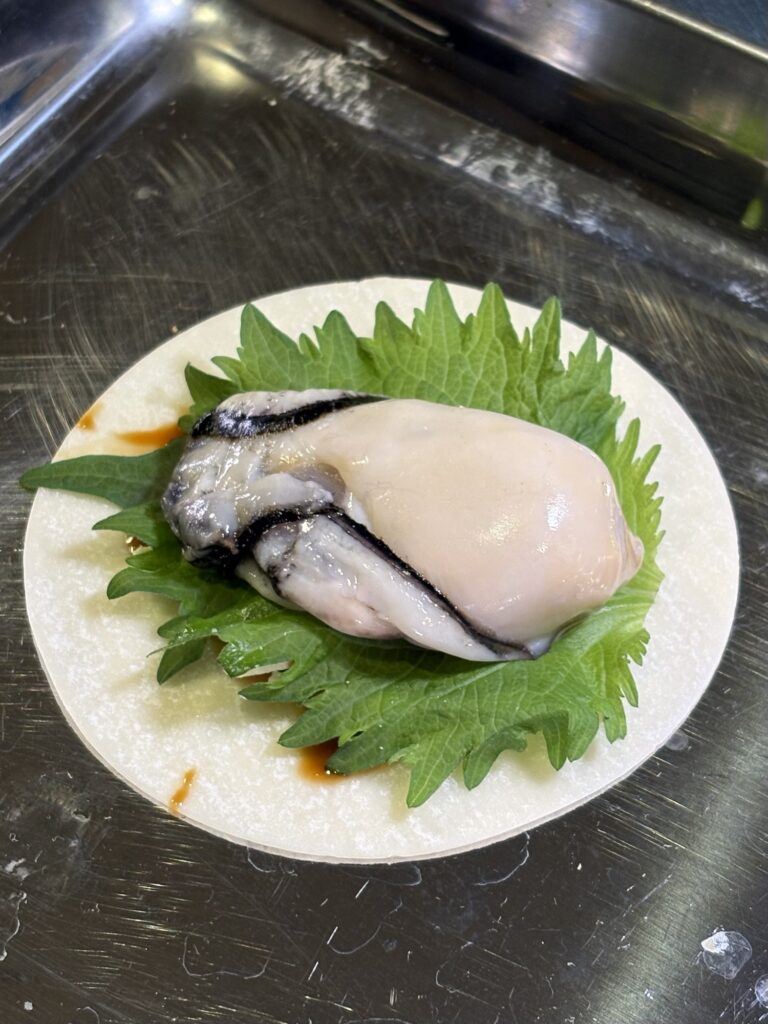 大葉の上に牡蠣を丸ごとのせた餃子