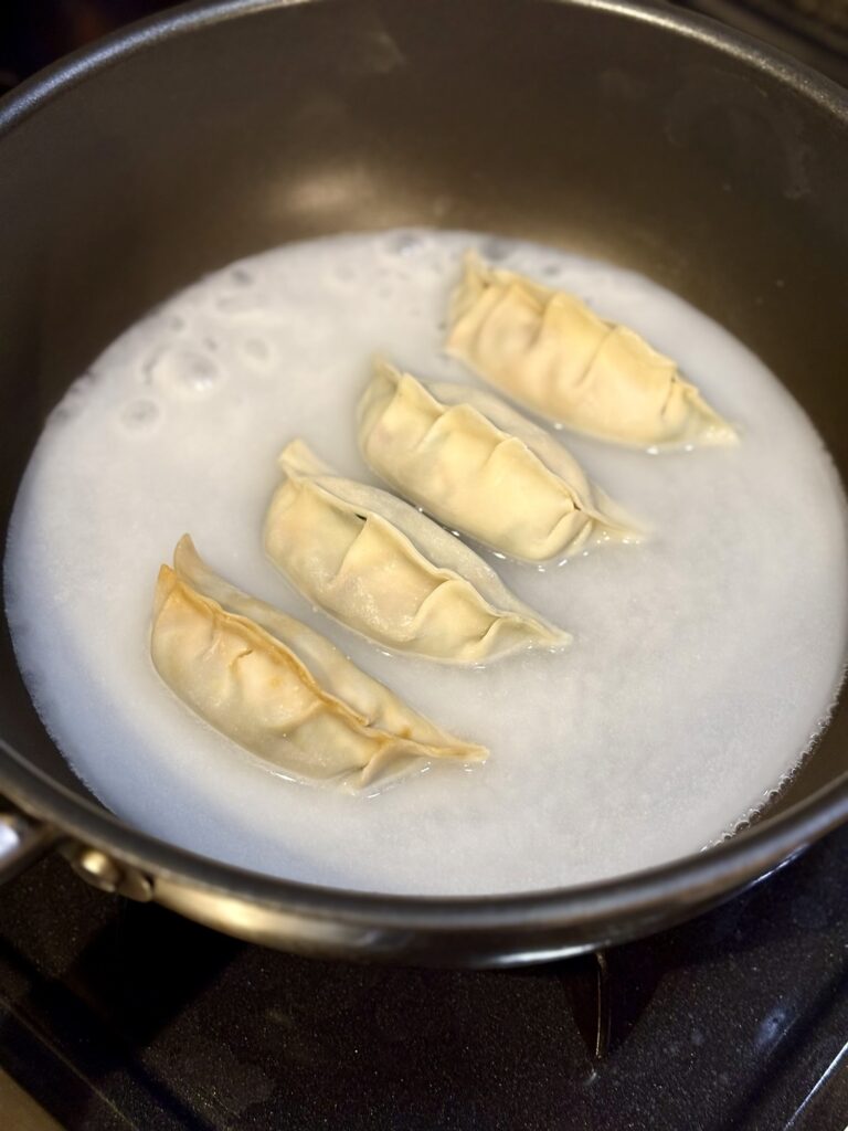 フライパンで牡蠣餃子を蒸し焼きにしている様子