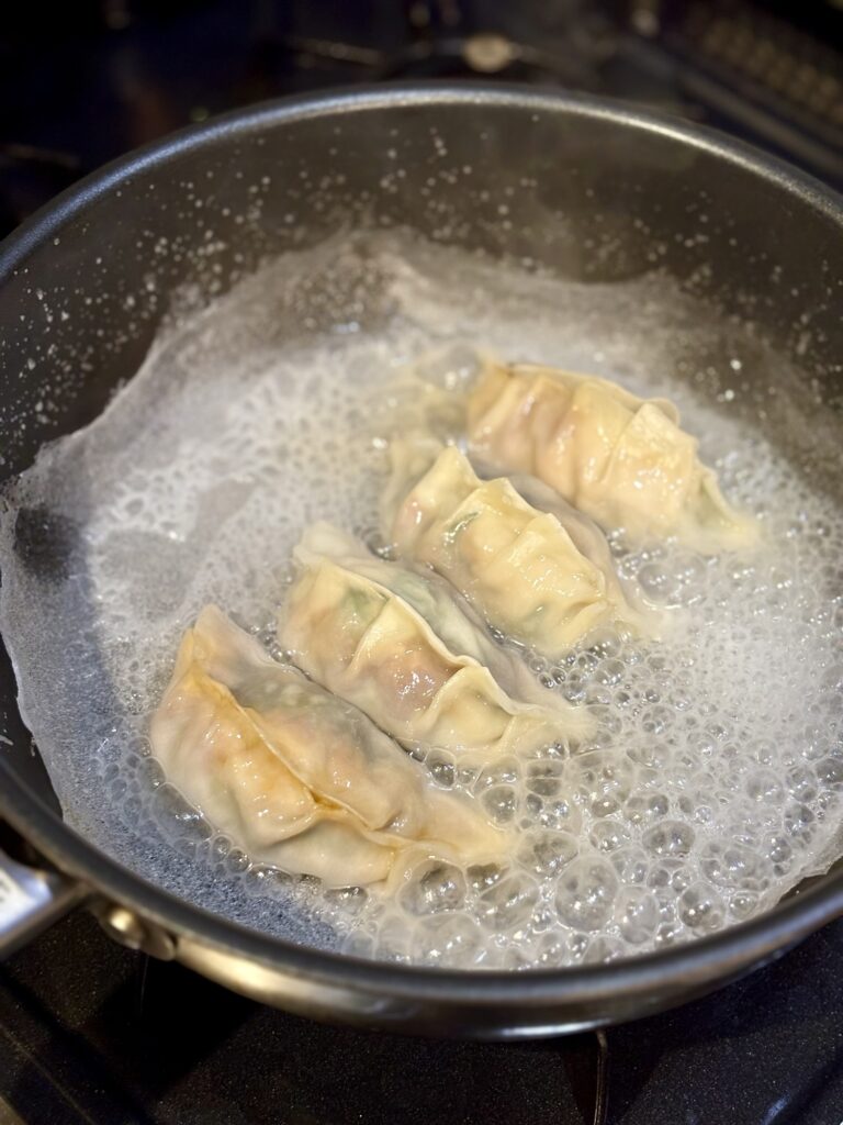 羽根つき餃子の水分が飛び泡立っているフライパン