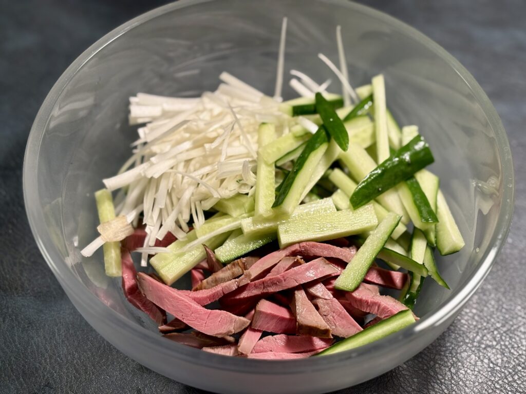 低温調理した牛ハツと胡瓜、長ネギをボウルに入れた様子