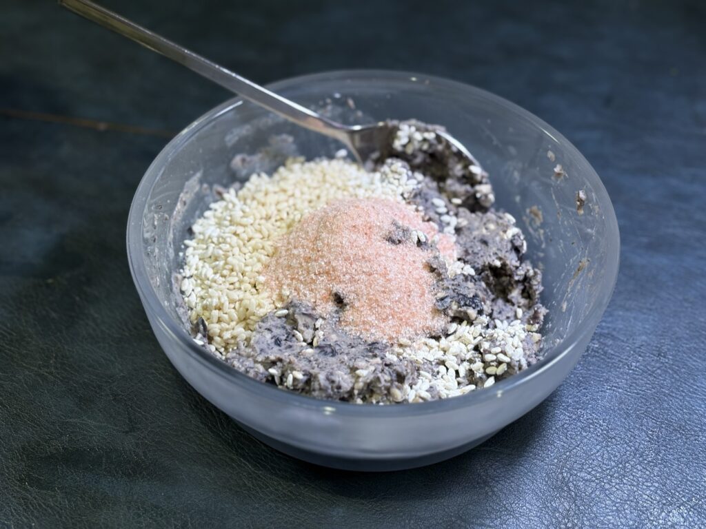 蒸し黒豆に米麹と塩を加えて黒豆麹味噌を仕込んでいる様子