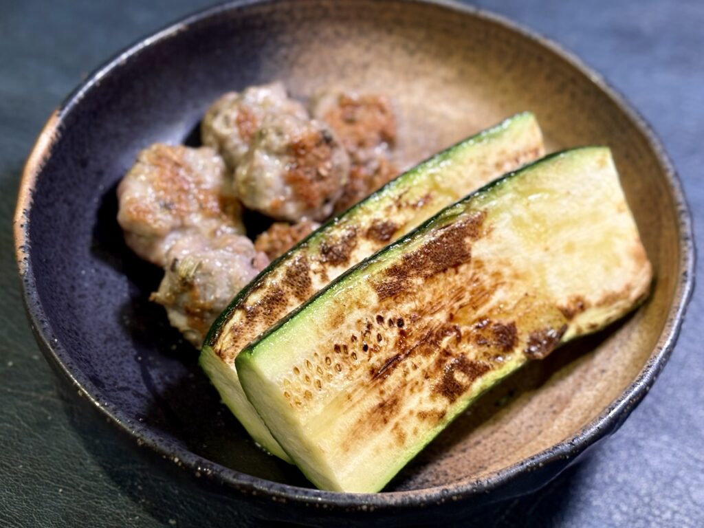 焼いたズッキーニとサルシッチャを皿にとる