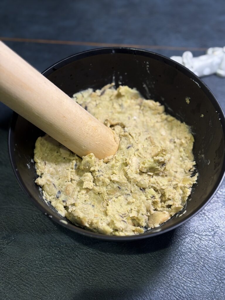 蒸したひたし豆をすりこぎでつぶしているところ