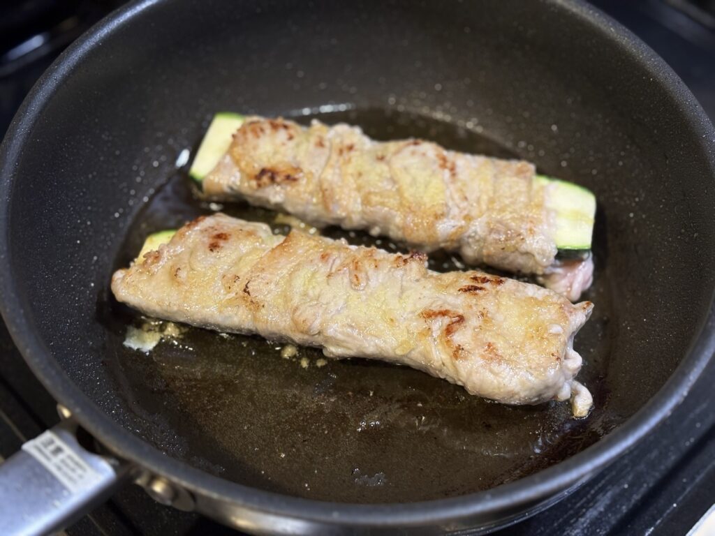 フライパンで豚の肉巻きズッキーニを焼いているところ