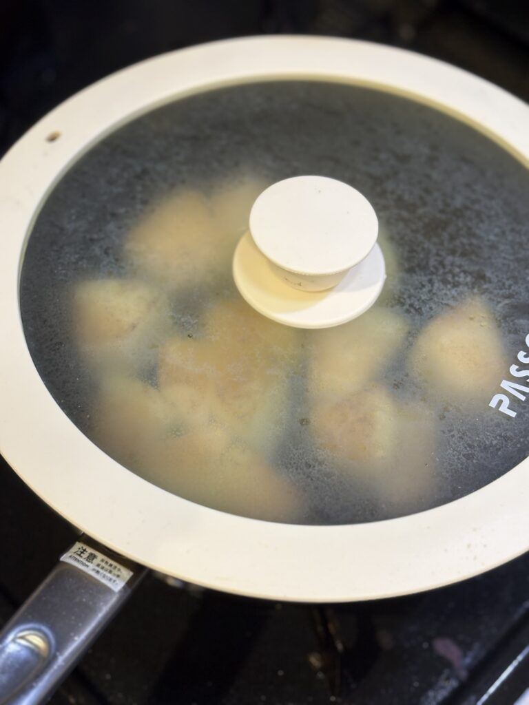 蓋をしたフライパンで焼き冬瓜を蒸し焼きにする様子