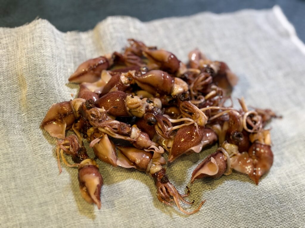 味噌床の容器でホタルイカをガーゼに包んで西京漬けにしている様子