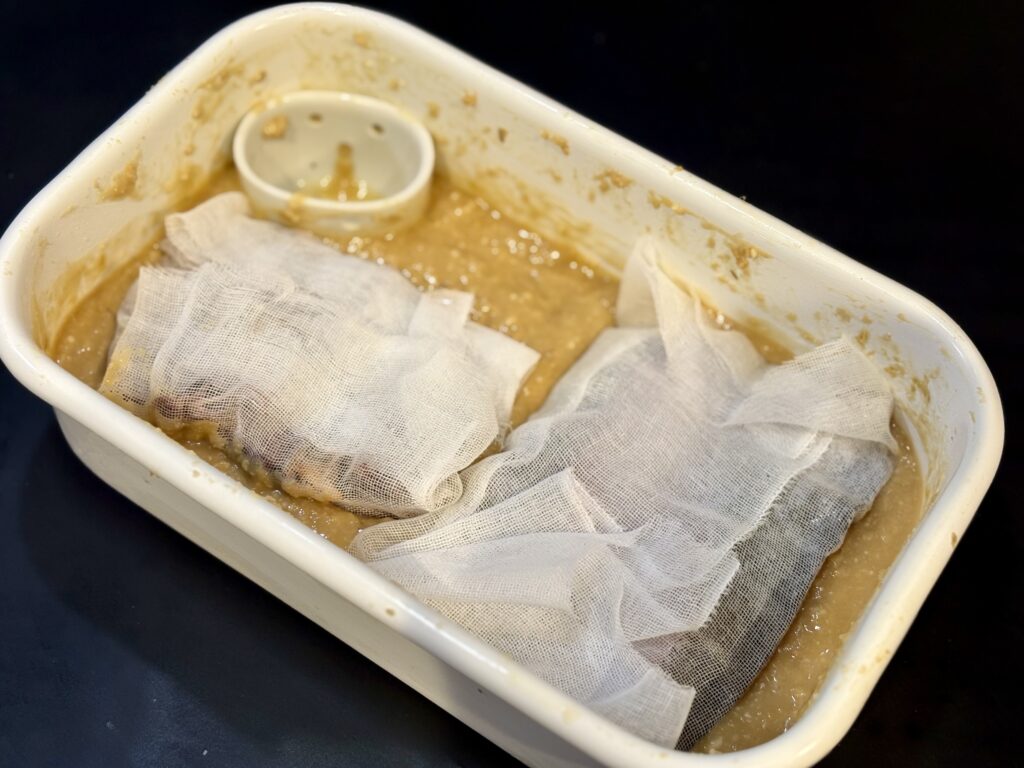 真鱈とホタルイカをガーゼで包み、味噌床で一緒に西京漬けにする仕込み