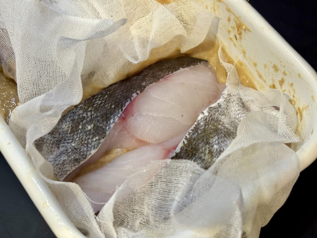 真鱈の切り身をガーゼで包み、味噌床で西京漬けにする仕込み工程