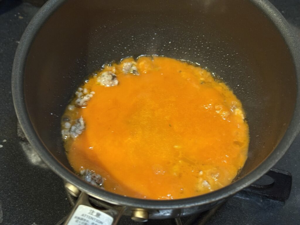 サルシッチャにトマトソースを加えて煮込む様子