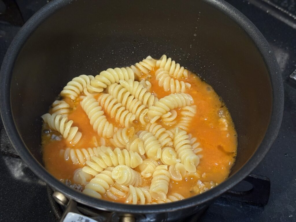 フジッリパスタをトマトソースに絡める工程