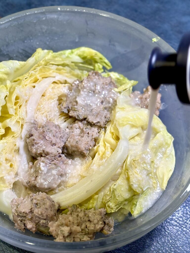 加熱した春キャベツと自家製サルシッチャに白い醤油麹ドレッシングをかける写真