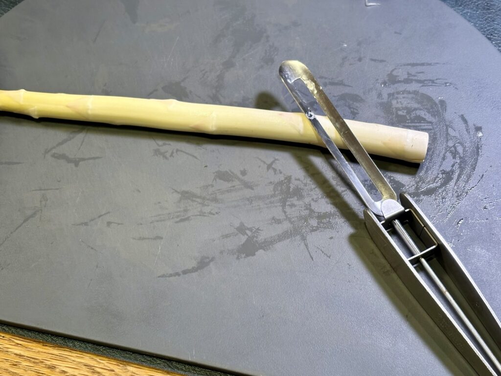 ホワイトアスパラの皮をピーラーで剥いている工程写真