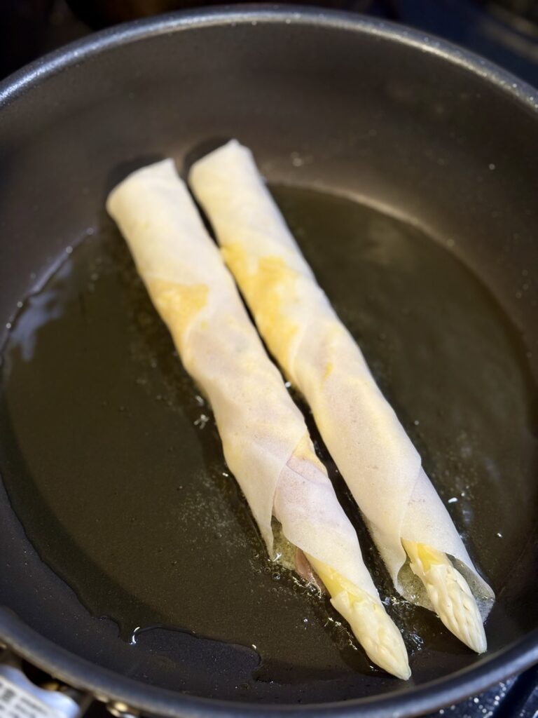 フライパンでホワイトアスパラ春巻きを揚げ焼きしている写真