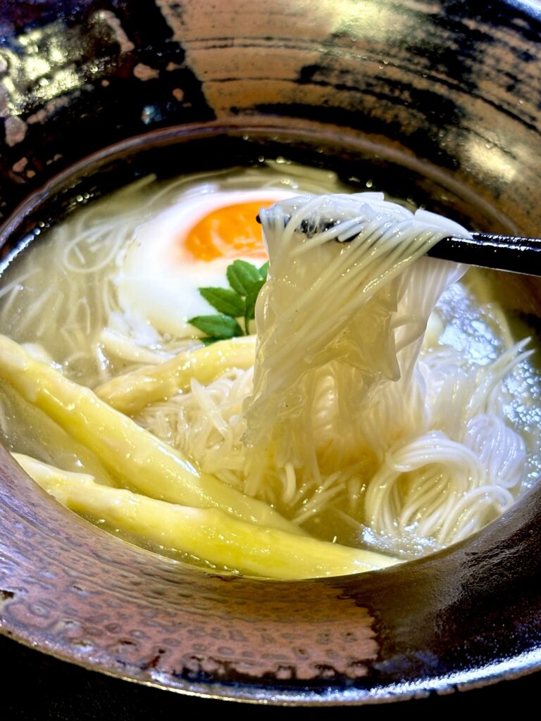 そうめんと細切りホワイトアスパラを一緒に箸で持ち上げた写真