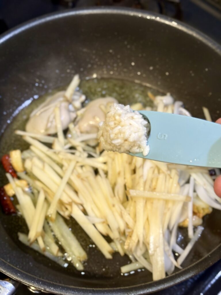 牡蠣のフライパンに新じゃが芋、新玉ねぎ、白い醤油麹を加える様子