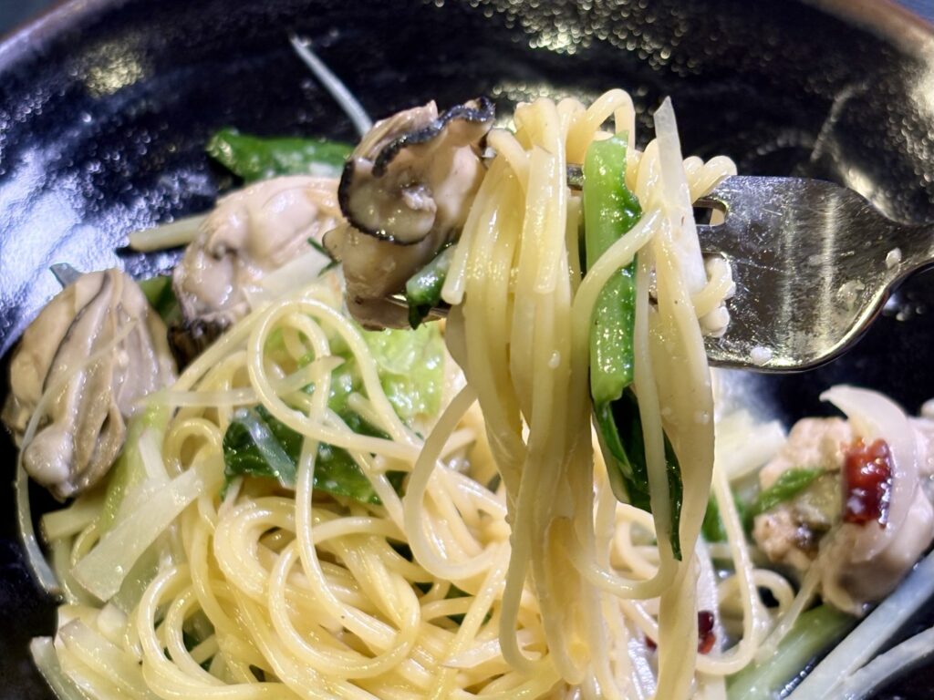 牡蠣と春野菜の黄金スープパスタを持ち上げた様子