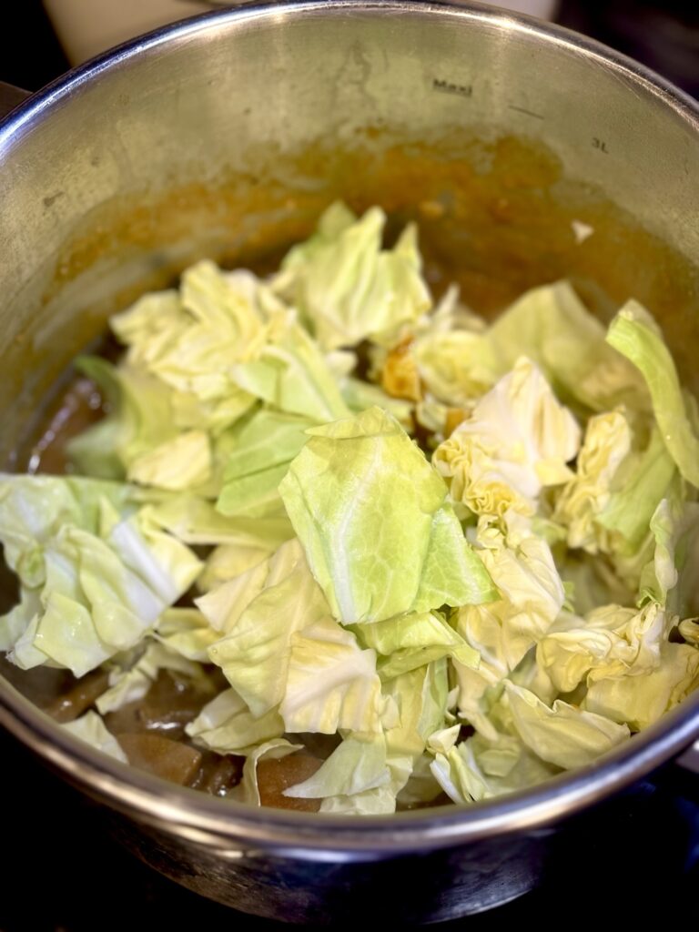 仕上げの魚出汁カレーに春キャベツを加えている様子