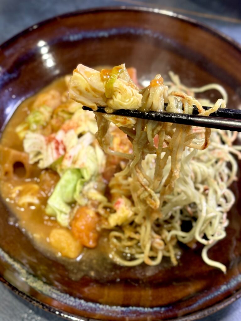 カレーを絡めたパリパリ茶そばを箸で持ち上げた様子